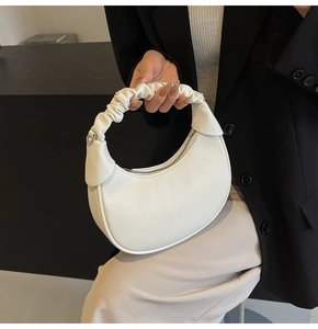 Detail of white pebbled leather crescent bag featuring a stylish scrunchie-style handle