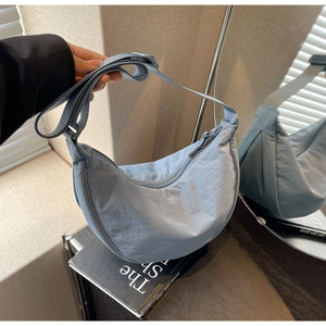 Detailed close-up of light blue nylon crescent bag with adjustable wide fabric strap