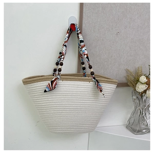Detail of woven straw tote bag with silk scarf wrapped handle and wooden bead accents