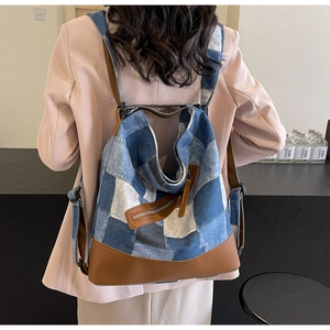 Detail of patchwork denim backpack with leather trim worn by model in casual setting