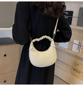 Detail of off-white dumpling bag showing lychee texture and gathered handle on model