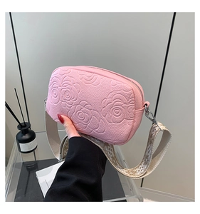 Close-up of pink crossbody bag featuring embossed rose patterns and textured faux leather