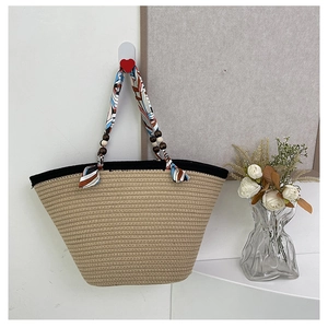 Detail view of woven straw tote bag featuring silk scarf handle and wooden beads