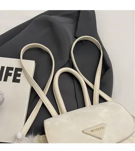 Detail of cream bucket bag showing slender shoulder strap and triangular metal logo