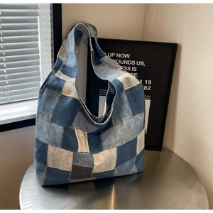 Close-up of patchwork denim tote bag with textured blue denim fabric and wide strap