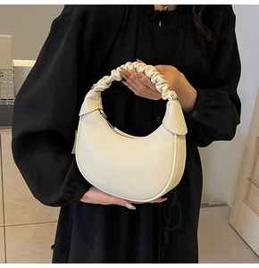 Detail of off-white crescent bag featuring lychee texture and pleated handle