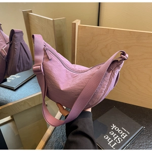 Detail of purple half-moon canvas bag with pleated texture and adjustable strap