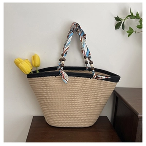 Detail of straw tote bag featuring vibrant silk scarf handles and brown wooden beads