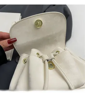 Detail of cream drawstring backpack showing metallic leather texture and gold hardware