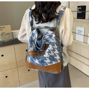 Rear view of woman wearing a blue geometric canvas backpack with brown leather trim detailing
