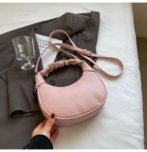 Pink lychee grain leather crescent bag with cloud handle on a minimalist background