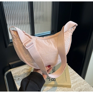 Detail of light pink crescent nylon bag showing wrinkled texture and adjustable strap