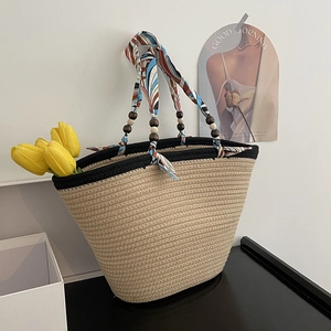 Detail of hand-woven straw tote bag with silk scarf handle and wooden bead accents