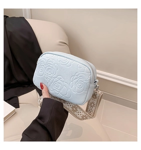 Detail showing 3D embossed rose pattern on light blue leather with jacquard strap