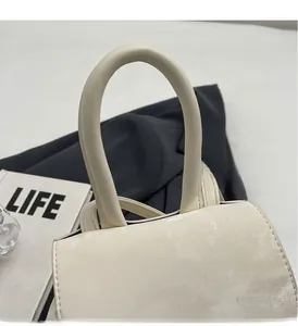 Detail of reinforced padded handle on white faux leather handbag with stone texture