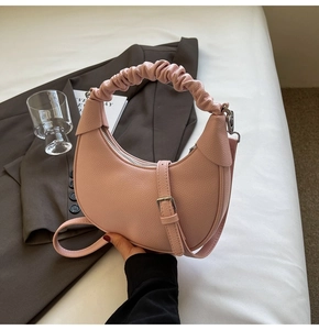 Detail of light pink crescent bag featuring lychee grain leather and scrunchie handle