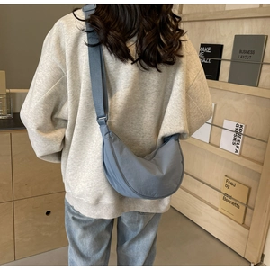 Rear view of a model wearing the Morandi blue crescent nylon bag with adjustable strap