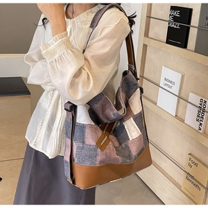 Detail view of large canvas patchwork tote bag with leather straps and metal zipper accents