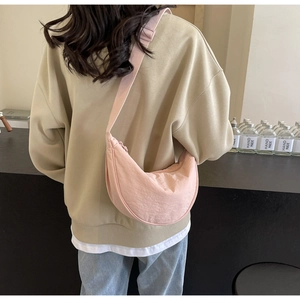 Rear view of a model wearing a pink crescent nylon crossbody bag with adjustable strap