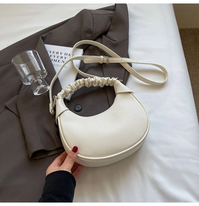 Detail of white crescent bag with lychee texture and scrunchie handle on a suit