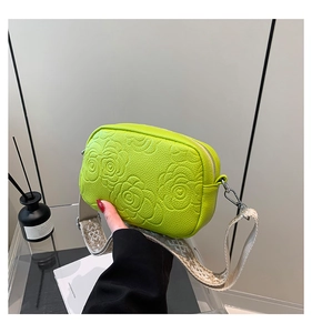 Detail showing embossed rose pattern and woven strap on neon leather square crossbody bag
