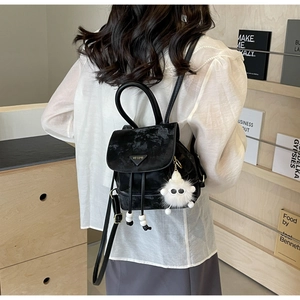 Detail of black velvet backpack with drawstring closure and cute plush monster charm
