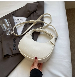 Detail of creamy white dumpling bag featuring scrunchie handle and lychee leather texture
