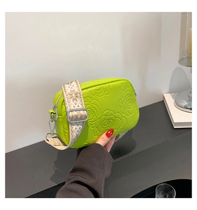 Detail of lime green embossed rose pattern on crossbody bag with jacquard woven strap
