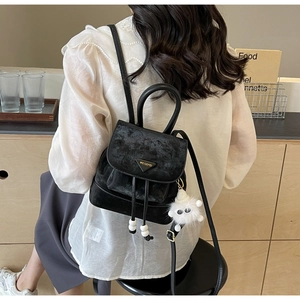 Detail of black suede backpack with drawstring closure and cute plush lamb charm pendant
