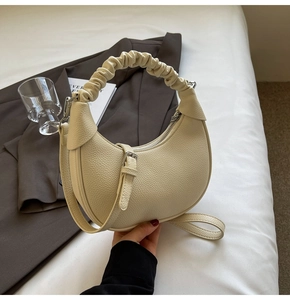 Close-up of cream lychee texture leather handbag with pleated handle and strap detail