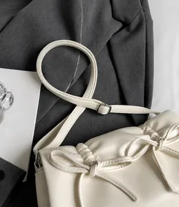 Détail du sac bandoulière plissé blanc cassé avec nœuds et longue bandoulière réglable