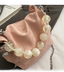Pink pleated cloud bag featuring oversized clear resin beaded handle and silver chain strap