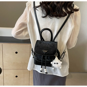 Detail of black velvet mini backpack featuring drawstring closure and fuzzy monster charm