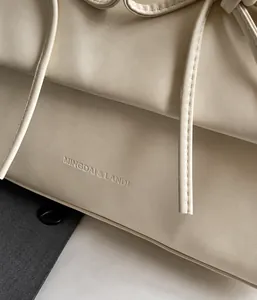 Détail de la sacoche plissée en cuir crème avec logo de marque gaufré de luxe