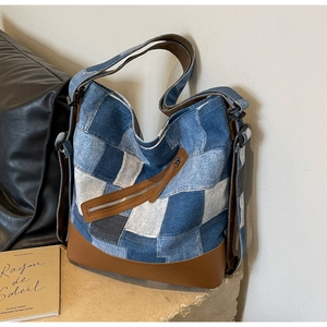 Close-up of patchwork denim tote bag with vintage blue panels and brown leather accents