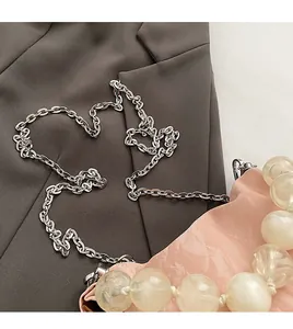 Close-up of pink bucket bag with silver metal chain strap and large yellow bead handle