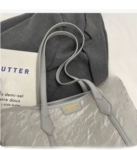 Detail of grey tote bag with pleated texture and brand label on minimalist background