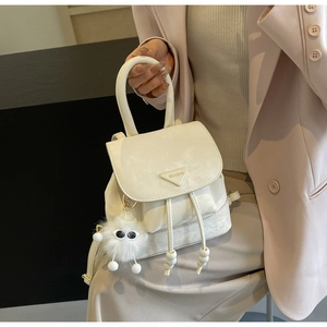 Detail of white mini bucket backpack with drawstring closure and plush eye charm