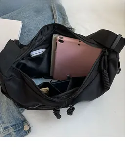 Geräumiger Innenraum einer schwarzen Umhängetasche mit Tablet, Schirm und Reißverschluss