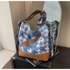 Detail view of blue houndstooth canvas tote with brown leather base and side zip pocket