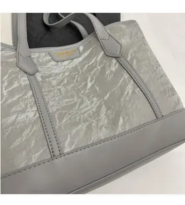 Close-up of gray tote bag featuring crinkled texture fabric and branded logo detail