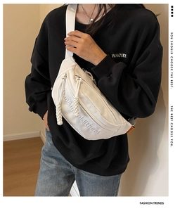 Close-up of white canvas waist bag featuring subtle embroidery and orange label detail