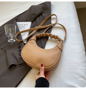 Detail of tan dumpling bag with lychee texture leather and adjustable shoulder strap