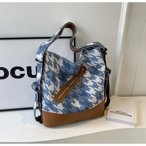 Detail of blue houndstooth canvas tote bag with brown leather trim and front zipper