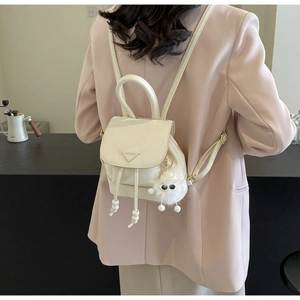 Detail view of cream mini backpack with drawstring closure and triangle plaque