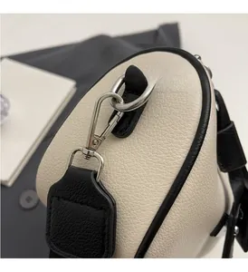 Detailed close-up of high-shine silver metal hardware on a cream pebbled leather bag