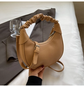 Detail of lychee textured leather crescent bag with ruched handle and silver hardware