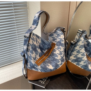 Detail of blue houndstooth canvas tote bag with brown leather trim and adjustable strap