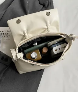 Vue intérieure montrant la grande capacité et la doublure noire du sac à bandoulière crème