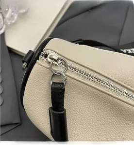 Macro detail of smooth silver zipper on off-white lychee grain leather handbag